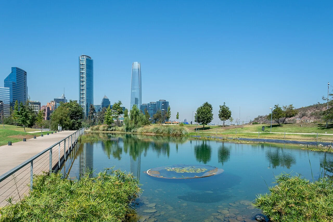 Laguna del Parque Bicentenario de Vitacura, con jardines y edificios de Santiago al fondo